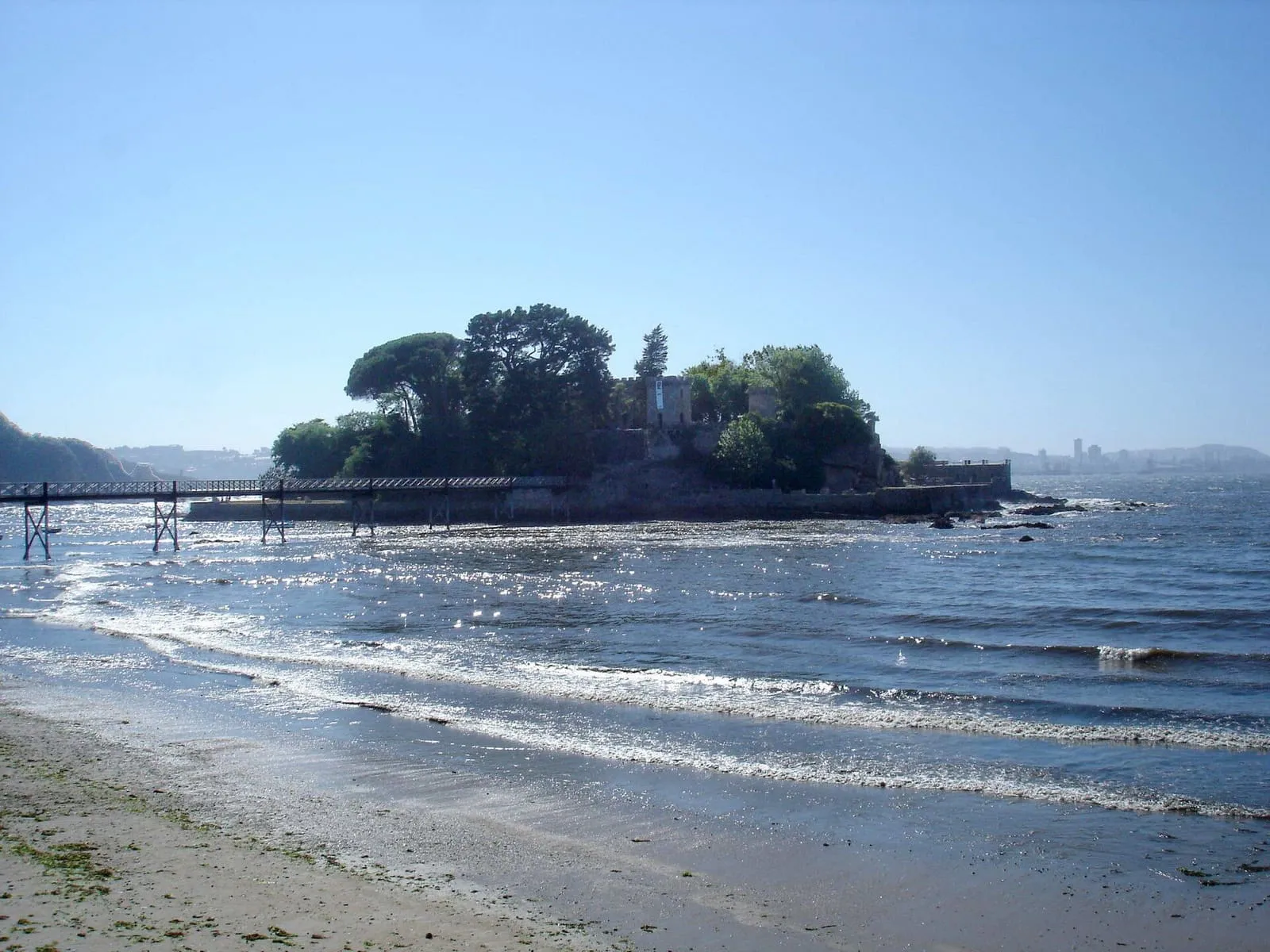 El castillo de Santa Cruz en un islote arbolado unido a la costa de Oleiros