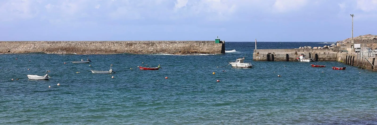 Escollera y barcas fondeadas en el puerto de San Cibrao, en Cervo