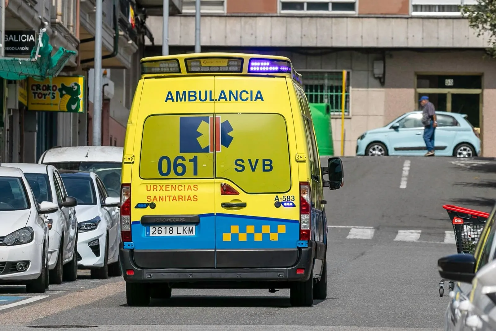 Ambulancia amarilla del 061 de Galicia vista por detrás, circulando por una calle