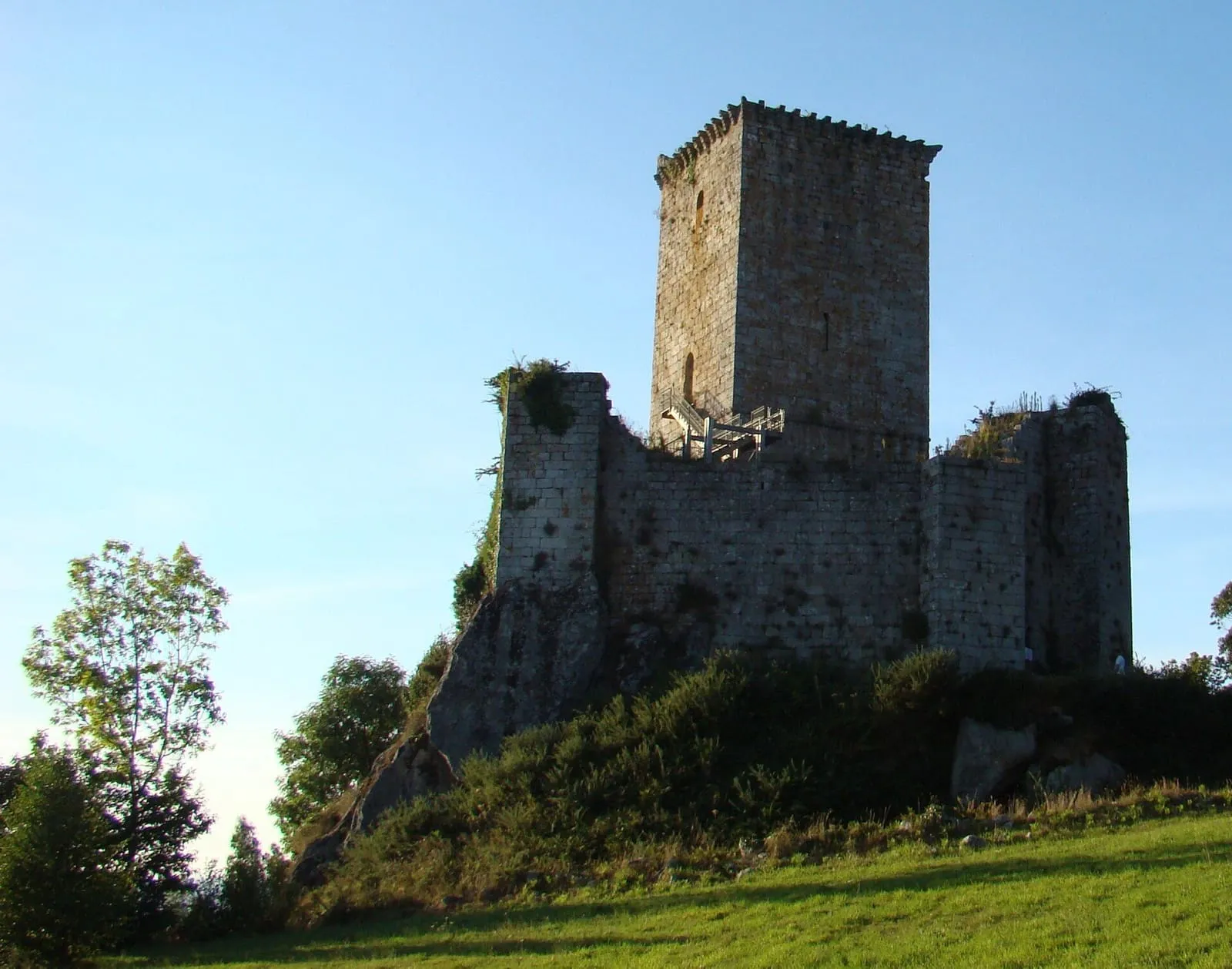 Torre y muros en ruinas del castillo de Andrade sobre una colina