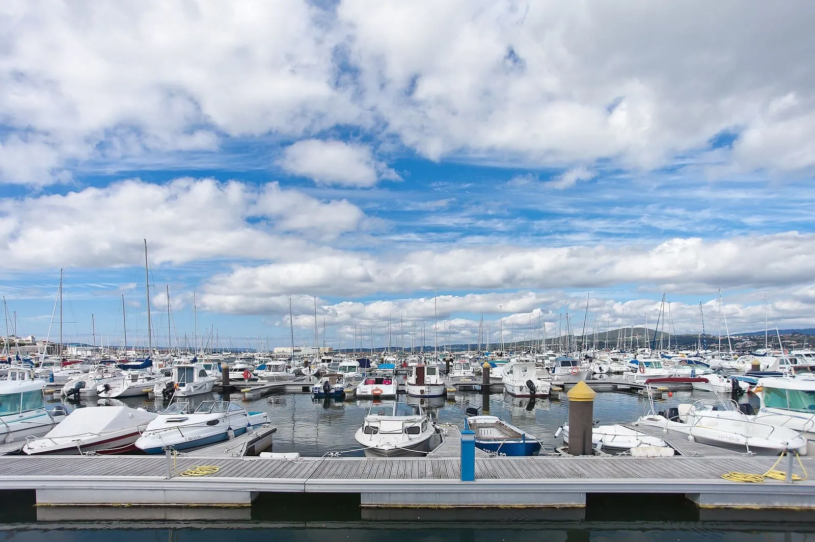 Puerto deportivo de Sada con veleros bajo un cielo con nubes