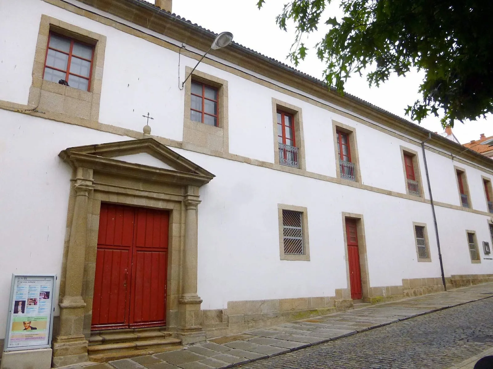 Fachada blanca con marcos de piedra y puerta roja del Centro Cultural Torrente Ballester, en Ferrol