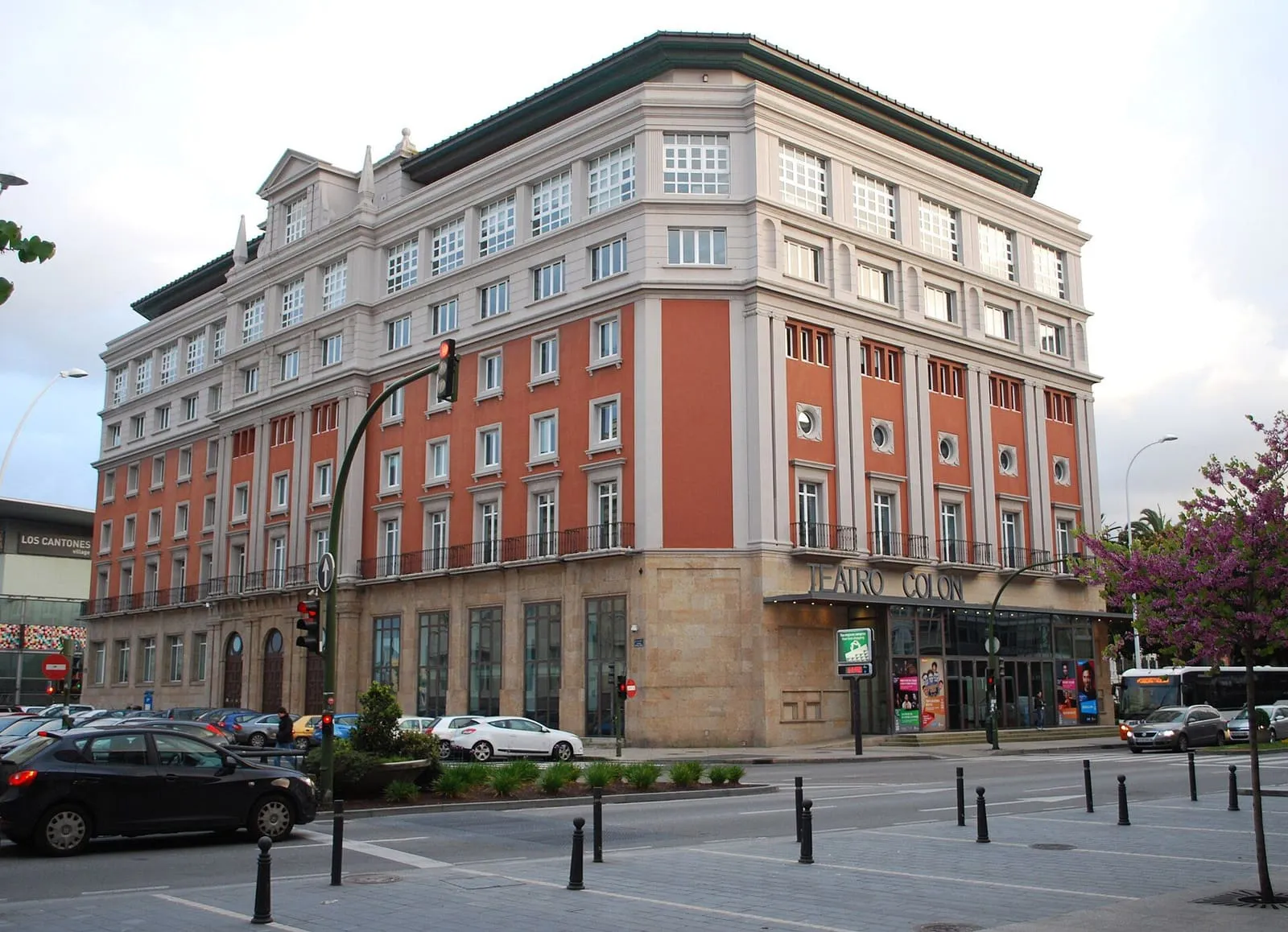 Edificio del Teatro Colón de A Coruña, con fachada de ladrillo rojizo y piedra en una esquina de los Cantones