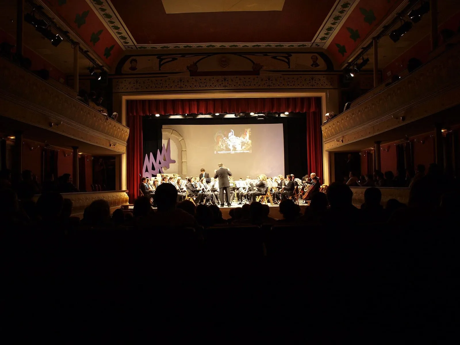 Interior del Teatro Pastor Díaz de Viveiro durante un concierto de banda, con palcos y telón rojo