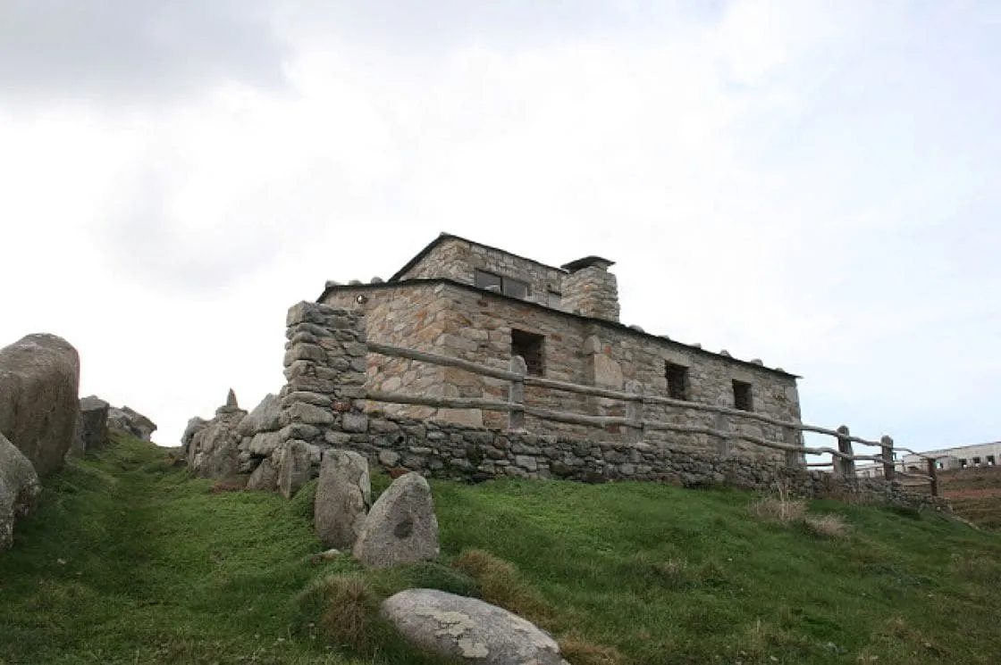 Edificio de piedra de la estación ornitológica entre rocas y prado
