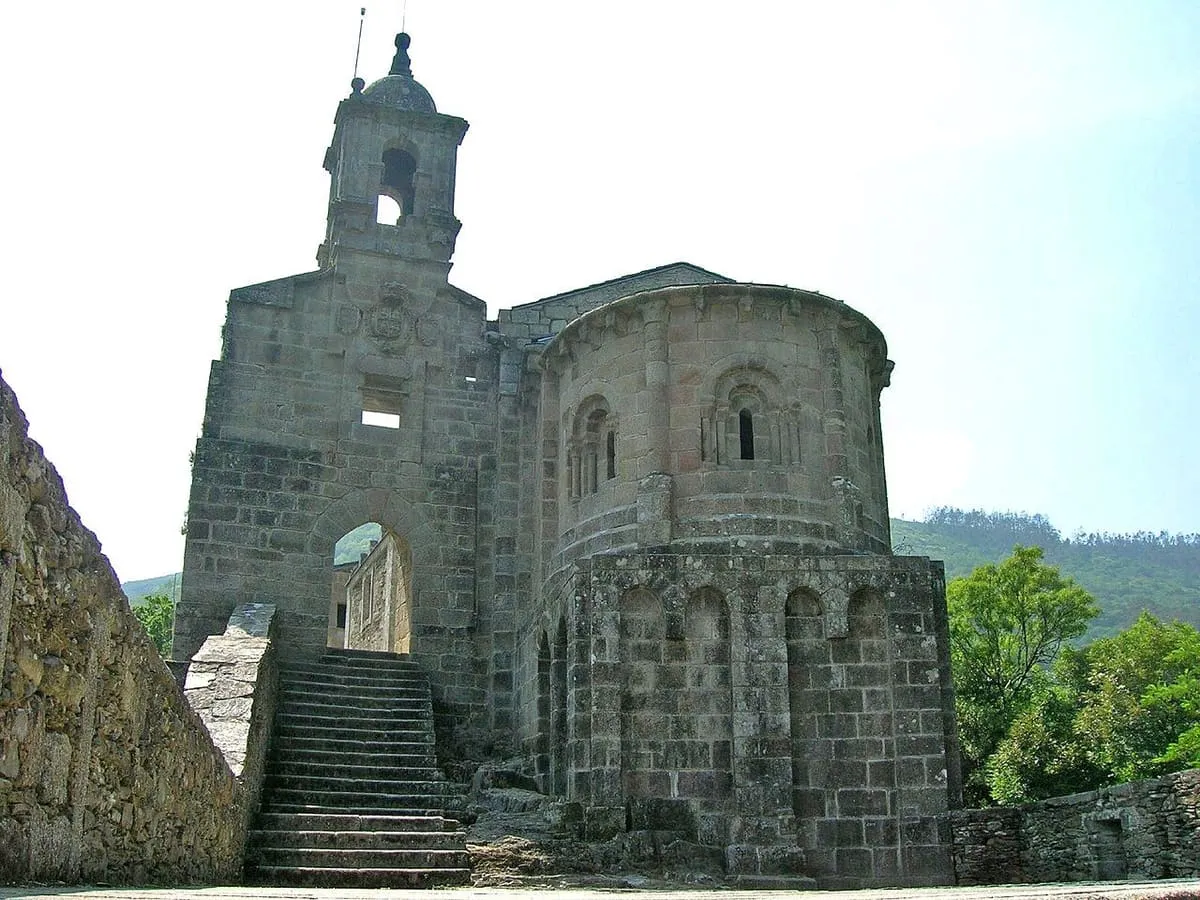 Ábside románico de piedra y espadaña del monasterio, con una escalera de acceso