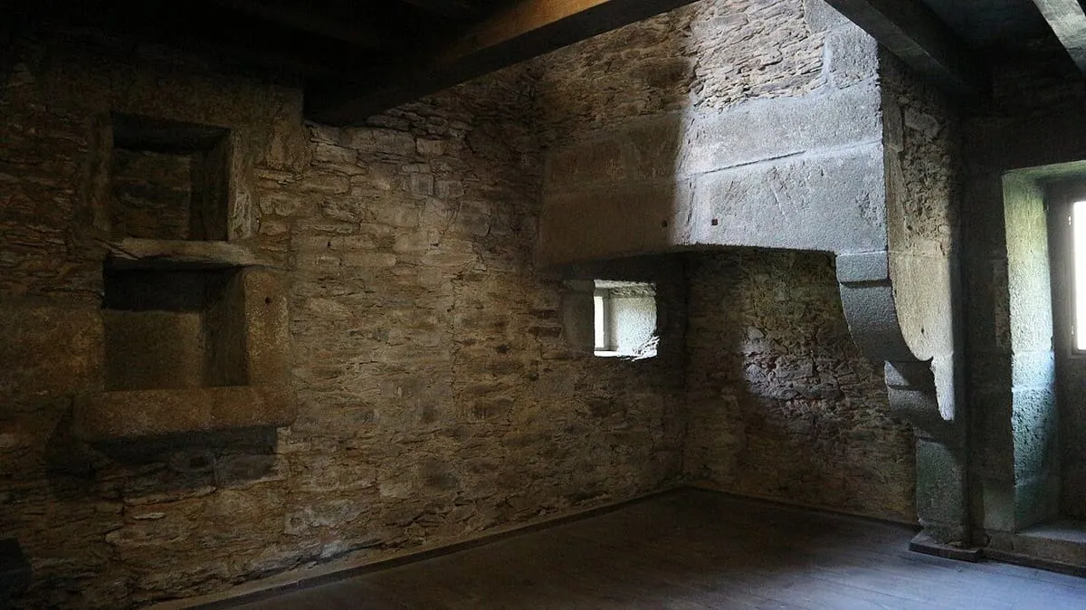 Estancia interior del monasterio, con muros de piedra, una ventana y suelo de madera
