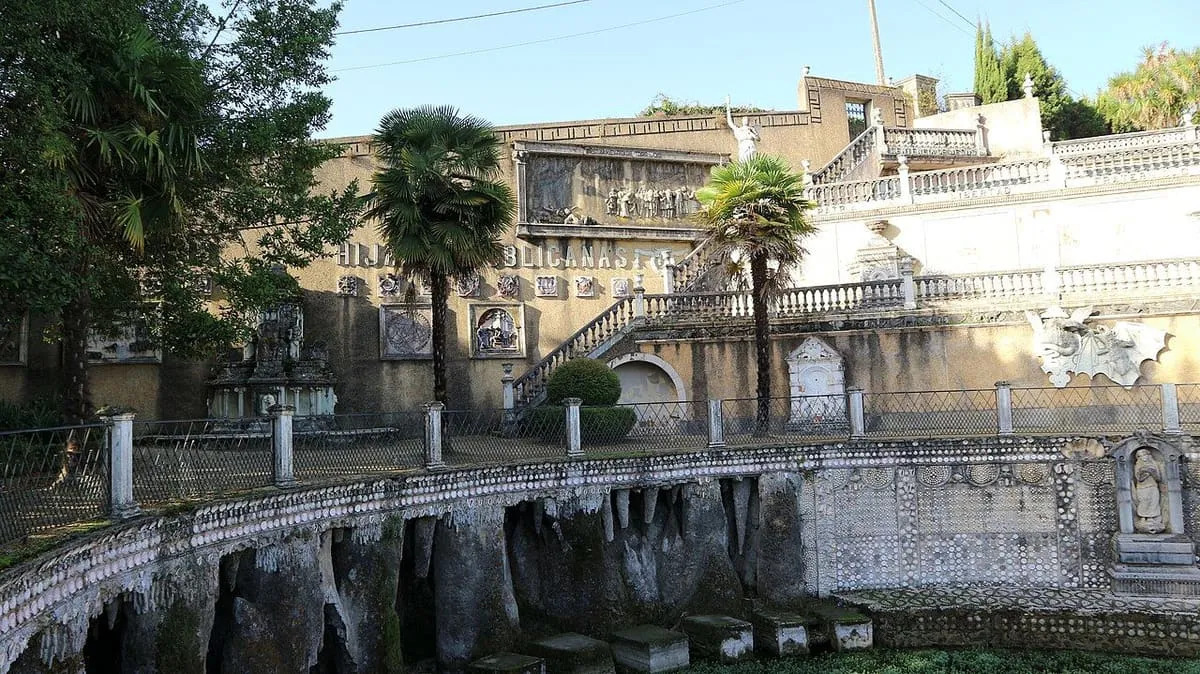 Estanque curvo con paredes decoradas, escaleras y terrazas con balaustradas y palmeras