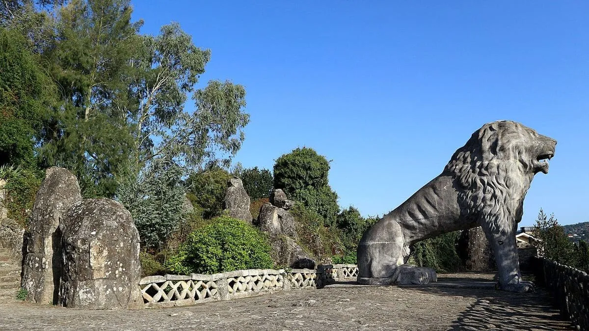 Gran león de piedra rugiendo sobre una terraza, junto a rocas esculpidas