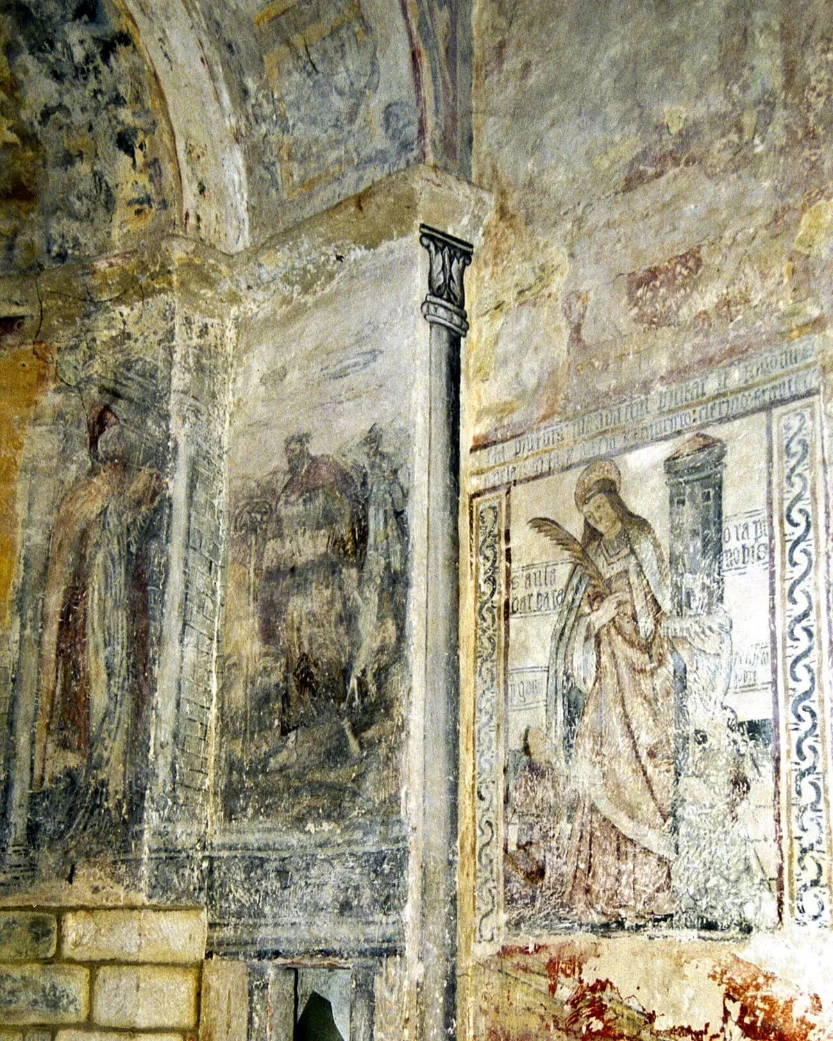 Restos de pinturas murales románicas en un muro, junto a una columna