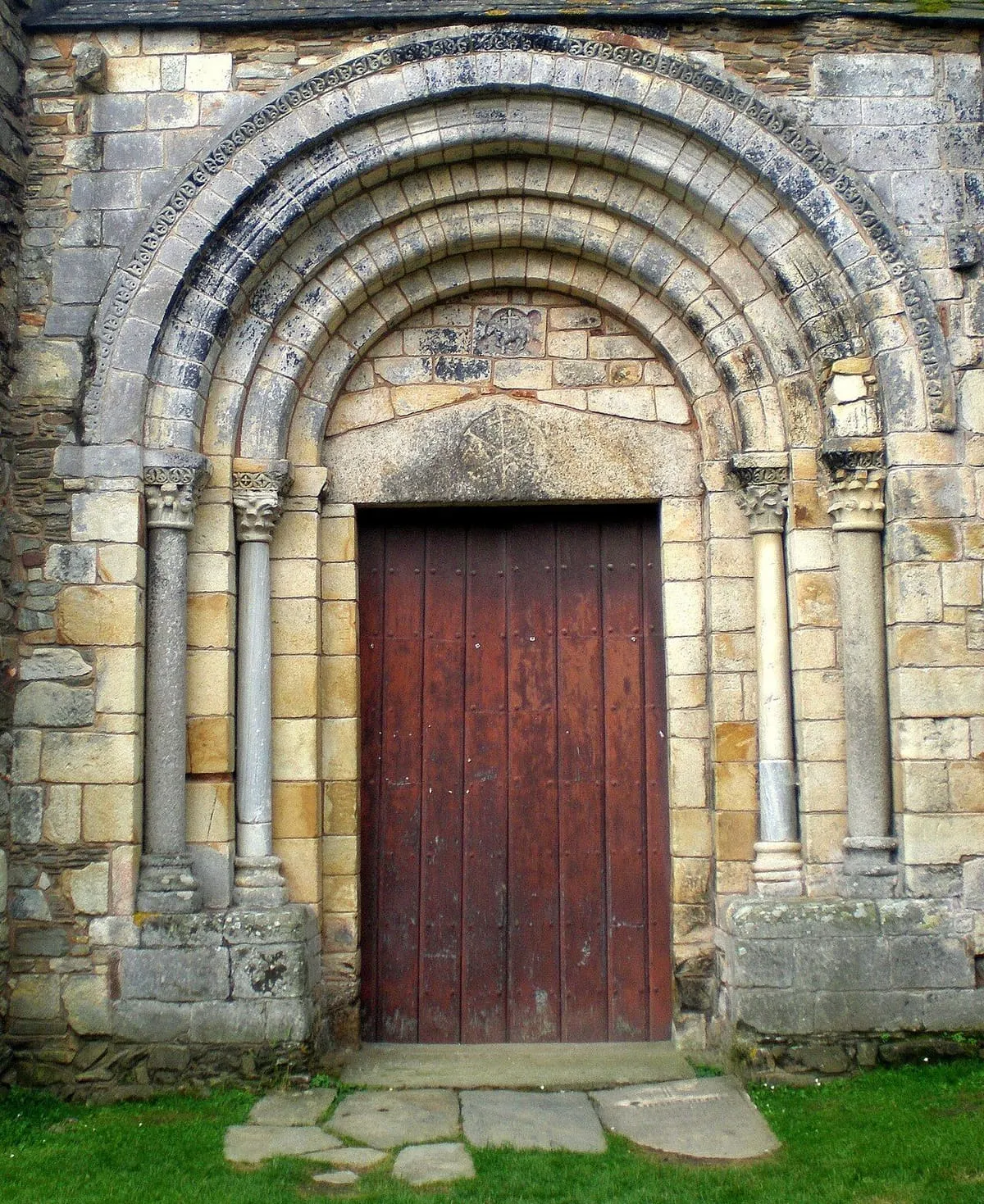 Portada de arcos de medio punto con arquivoltas y puerta de madera roja