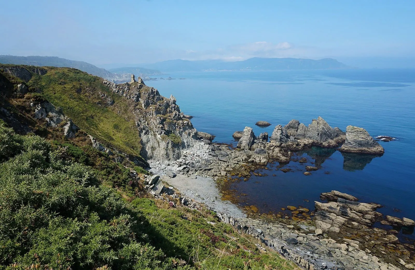 Acantilados de Loiba sobre aguas azules, con rocas en el mar